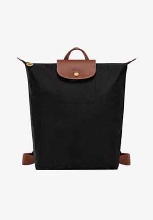 Schwarzer Nylon-Rucksack mit braunen Lederakzenten. Verfügt über einen Tragegriff, eine Fronttasche und verstellbare Gurte. Detail mit goldfarbenen Beschlägen.