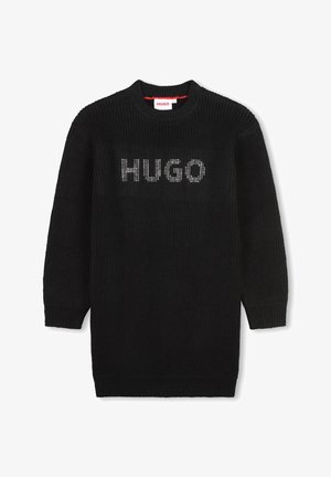 Pull en tricot noir avec un col rond, arborant le mot "HUGO" en clous argentés sur le devant. Manches longues et poignets côtelés.