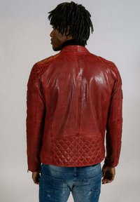 Veste en cuir rouge avec des accents matelassés sur les épaules et le dos, affichant une texture lisse et une coupe ajustée. Vue arrière présentée.