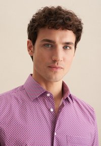 Camicia a maniche corte con bottoni di colore rosa con un motivo geometrico. Presenta un colletto classico e una texture di tessuto liscia.