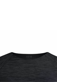 Černé atletické tričko s kulatým výstřihem, s texturovanou látkou a raglánovými rukávy. Na límci je zobrazeno logo "GORE".