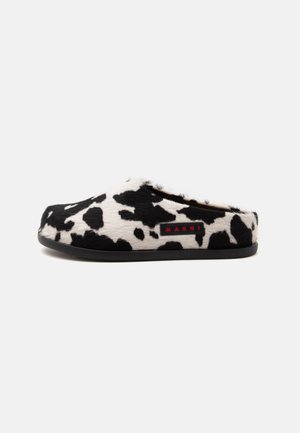 Čierno-biele slip-on topánky s potlačou kravy, plochou čiernou podrážkou a malým červeným logom Marni na boku.