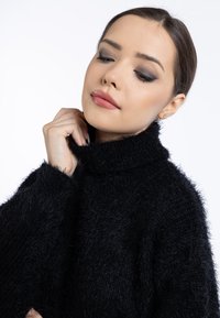 Schwarzer Rollkragenpullover aus einem flauschigen Material, mit hohem Kragen und weiten Ärmeln, weichem Griff und minimalen Details.