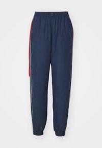 Marinebukser med elastisk talje, sidestripe i rød og hvit, og smalnende benåpninger. Laget av lett, glatt stoff.