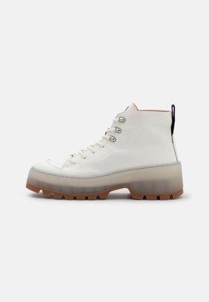 Weißer High-Top-Lederstiefel mit dicker durchsichtiger Sohle und braunem Profil, silbernen Ösen, weißen Schnürsenkeln und schwarzem Fersen-Zuglasche.