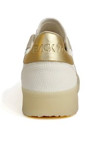Sneaker bianco con superficie in pelle testa di moro e dettaglio sul tallone in oro metallico. Il tallone presenta una scritta in rilievo "BACK 70". Suola in gomma.
