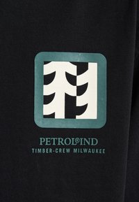 Zwarte katoenen crewneck sweatshirt met een wit en turkoois logo met gestileerde bomen en de tekst "PETROLIND TIMBER-CREW MILWAUKEE."