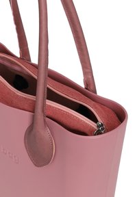 Vaaleanpunainen nahkakassi, jossa on kaksi kantohihnaa, teksturoitu sisututkimus, vetoketjullinen lokero ja sileä pinta.