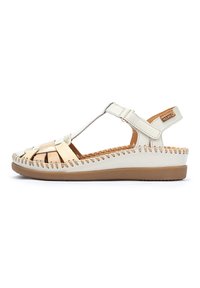 Sandalia de cuero blanca y beige con parte superior trenzada, lados abiertos, correa ajustable y plantilla acolchada. Suela de goma marrón clara y detalles de costura.