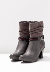 Botas de tobillo grises con un acabado de cuero suave, parte superior de tela arrugada, acentos a rayas en contraste y un tacón grueso para mayor estabilidad.