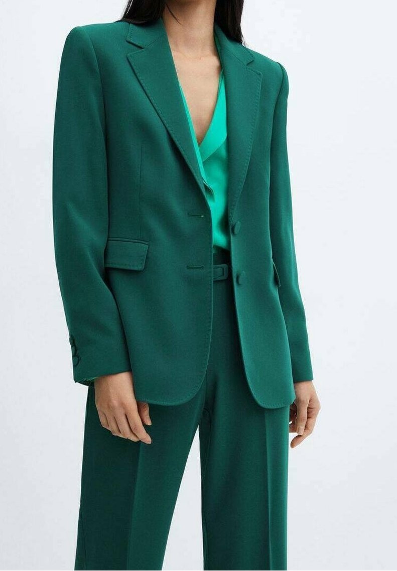 Blazer turchese e pantaloni abbinati, taglio sartoriale, rever classici, due bottoni e tasche laterali; tessuto liscio, leggermente lucido con un aspetto strutturato.