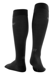 Calcetines de compresión en negro sólido, con una textura acanalada, diseño hasta la rodilla y un detalle de logo sutil en el lateral y en la parte inferior.