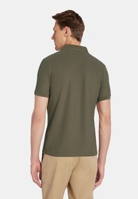 Oliwkowa koszulka polo z krótkim rękawem wykonana z teksturowanej tkaniny, z klasycznym kołnierzykiem; widok z tyłu pokazujący czyste linie i dopasowany krój.