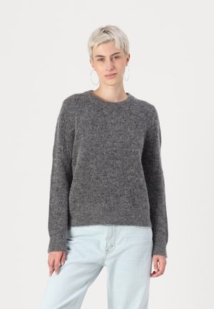 Grauer Wollpullover mit Rundhalsausschnitt, langen Ärmeln und einer weichen, strukturierten Oberfläche. Kombiniert mit hellblauen Jeans und minimalen Hardware-Details.