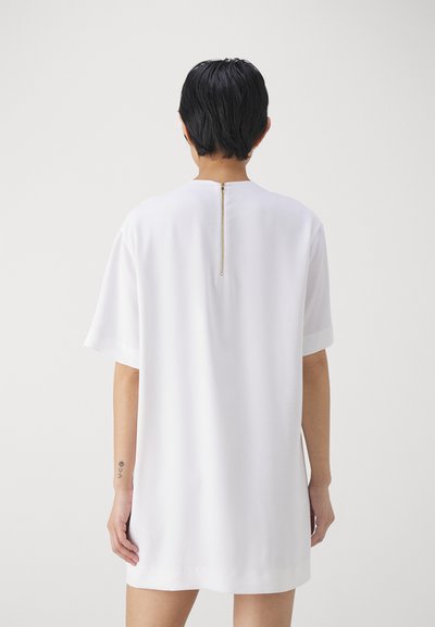 Rochie albă scurtă, cu o croială lejeră, mâneci scurte și detaliu cu fermoar auriu pe spate. Material fin, ușor, cu un design simplu.