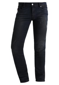 Pantalones vaqueros de denim azul oscuro con corte ajustado, que presentan sutiles áreas desgastadas y un estilo clásico de cinco bolsillos. Cierre con botón de metal y cremallera.