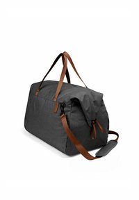 Šedá látková sportovní taška s hnědými koženými uchy a nastavitelným ramenním popruhem. Disponuje zipem na vrchu a minimalistickým designem.