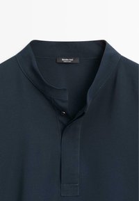 Tmavě námornicky modrá košile s mandlovým límečkem a jediným černým knoflíkem na předním pásku, uvnitř s visačkou značky Massimo Dutti.