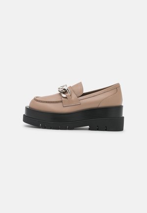 Mocasines de plataforma de cuero beige con un detalle de cadena plateada, que presentan una suela negra con relieve y un diseño de punta redonda.