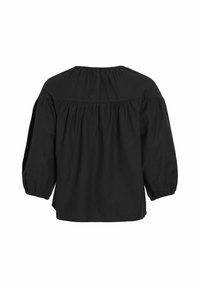 Melna kokvilnas blūze ar apaļu kakla izgriezumu un savelktu plecu daļu. Iezīmē brīvi krītošas, pūkainas piedurknes un brīvu siluetu.