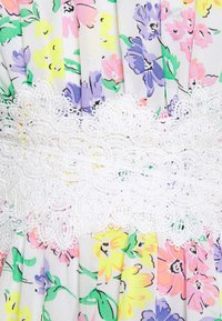 Robe à motif floral en tissu souple avec des fleurs violettes, jaunes et roses ; bordure en dentelle blanche ajoutant un détail délicat. Design plissé.