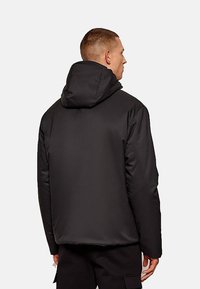 Giacca imbottita nera con cappuccio, caratterizzata da una texture liscia, vestibilità leggermente ampia e design minimalista. Senza motivi o dettagli visibili.