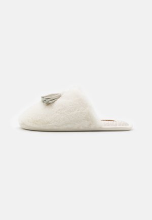 Witte, pluizige slippers met een zachte textuur en een decoratieve grijze kwast bovenop. Bevatten een platte zool en een open achterkant ontwerp.