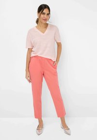 Lyserød V-hals t-shirt parret med koralfarvede tapered bukser. Sættet har en afslappet pasform, blød tekstur og metaliske spidse ballerinaer.