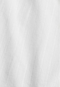 Tissu blanc avec de subtiles rayures verticales texturées et un délicat motif de broderie en forme de chaîne.