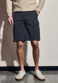 Námořnické cargo šortky s bočními kapsami, vyrobené z bavlněné směsi, s rovný střih a lemem těsně nad kolenem. V kombinaci s bílými teniskami.