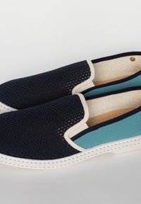 Marineblauwe mesh instappers met een crèmekleurige kraag en turquoise accent. Voorzien van een getextureerde rubberen zool en geperforeerde binnenvoering.
