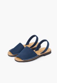 Granatowe skórzane sandały z odkrytymi palcami i zapięciem z tyłu. Posiadają kontrastujące białe szwy oraz teksturowana podeszwa.