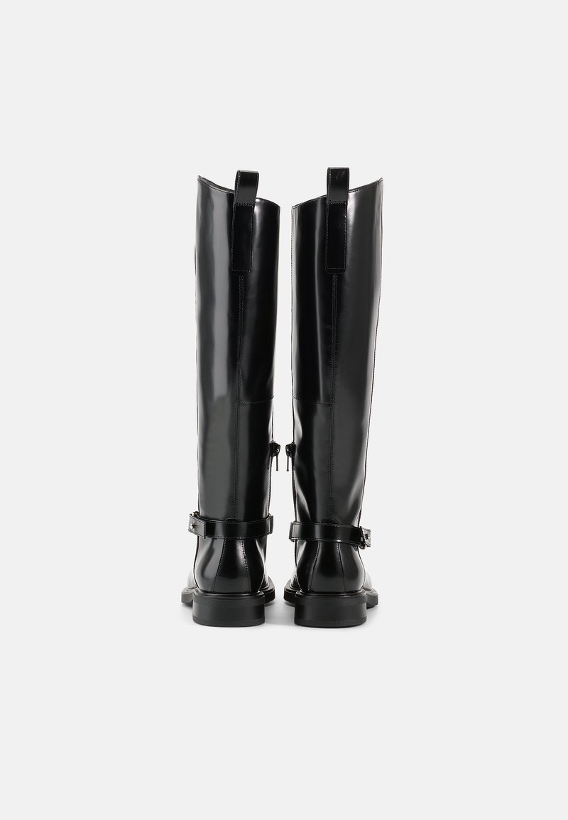 Schwarze kniehohe Stiefel mit glänzender Oberfläche, ausgestattet mit zwei verstellbaren Riemen und einer robusten Sohle. Die Rückansicht zeigt vertikale Nähte und Schlaufen.