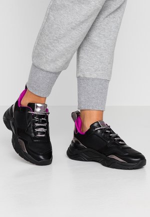 Baskets de sport noires avec des accents roses, cuir texturé, détails métalliques, lacets réfléchissants et semelle épaissie.