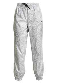 Nike sweatpants i ett ormskinsmönster, främst grå, med en elastisk midja med dragsko och åtsittande ankle cuffs.
