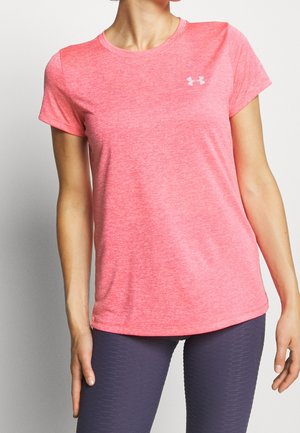 Femme portant un t-shirt de sport rose vif à manches courtes avec un petit logo blanc sur la poitrine et un legging gris foncé texturé.