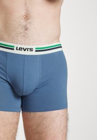 Kék pamut bokszernadrág fehér derékkal, fekete és zöld csíkokkal, a Levi's logóval középen elhelyezve elöl.