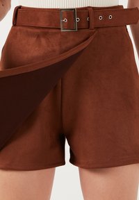 Hnědé krátké nohavice z umělé suroviny s vysokým pasem a širokým opaskem s obdélníkovou stříbrnou sponou a dvěma dekoračními poutky na opasek. Hladká textura.