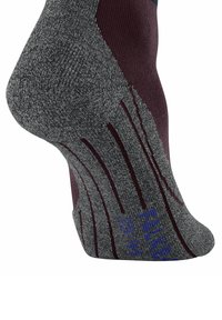 Primo piano di una calza grigia testurizzata con una sezione bordeaux, che mostra linee di presa e segni di dimensione in blu sul fondo.