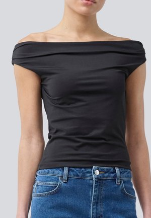 Haut noir décolleté fabriqué en tissu lisse, présentant un design ajusté et un doux drapé au niveau de l'encolure. Associé à un jean en denim bleu.