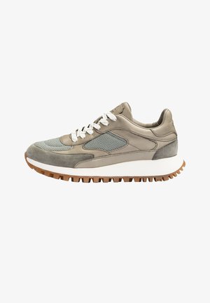 Lage sneaker in beige en grijs met witte veters, meshpanelen en een witte zool met een bruine geribbelde buitenzool.