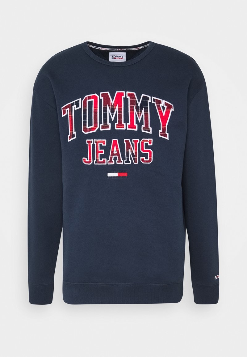 Sweat-shirt bleu marine à manches longues avec "TOMMY JEANS" en grandes lettres rouges et blanches et un petit logo de drapeau rouge et blanc en dessous.