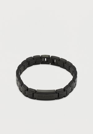 Bracelet à maillons en métal noir avec fermoir rectangulaire gravé "HILFIGER" sur fond blanc.