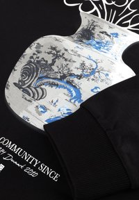 Svart sweatshirt med en stor grafik i silver, blått och grått som visar blommönster och böjda mönster, med texter.