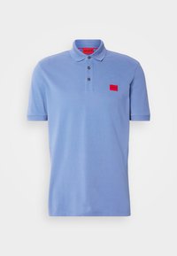 Polo bleu clair à manches courtes avec trois boutons noirs et un petit patch logo rectangulaire rouge sur le côté gauche de la poitrine.