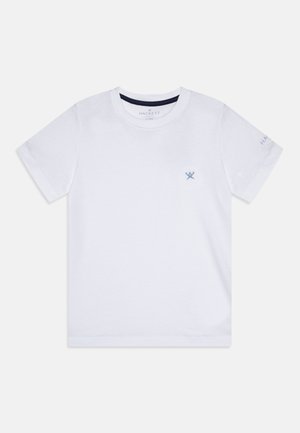 Hvid T-shirt med korte ærmer og rund hals med lille blåt krydset årer-logo på brystet og diskret tekst på venstre ærme.