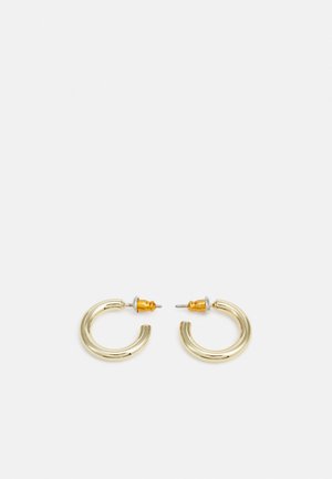 Guldtonade hoopsmycken med en slät, rund form och en polerad yta. Har orangea detaljer på baksidan för säker förslutning.
