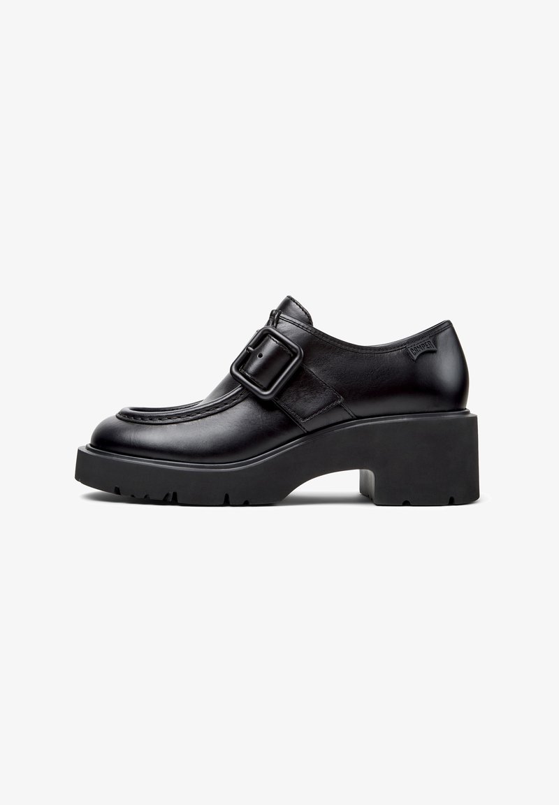 Chaussure en cuir noir avec talon épais, semelle épaisse et large boucle carrée sur le côté.