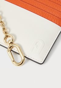 Lærerkortholder med oransje teksturert overflate og hvit aksent. Har en gullkjede og detaljer i hardware, preget logo.