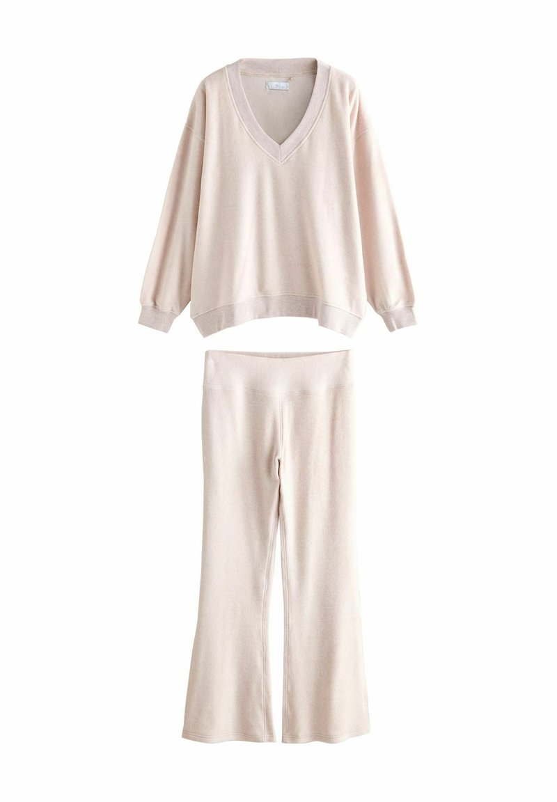 Jasno beżowy zestaw odzieży domowej składający się z rozpinanego swetra z dekoltem w serek i rozszerzanych spodni. Wykonany z miękkiego materiału o gładkiej fakturze.